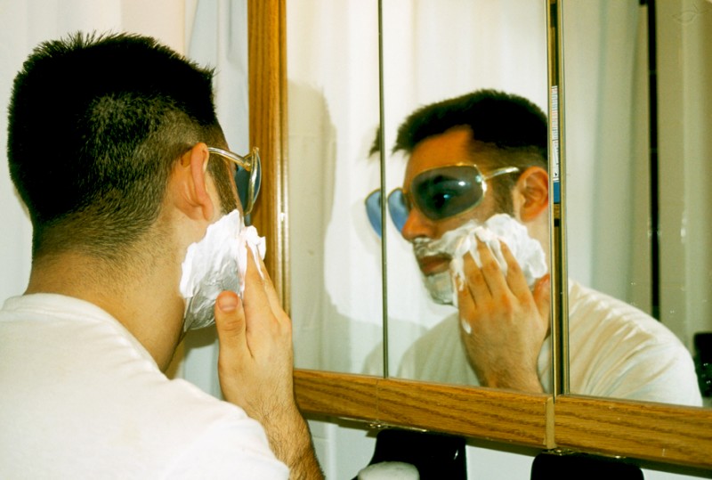 Jonathan wearing Blue Sunglasses while shaving, © Margaret Schnipper, photographer