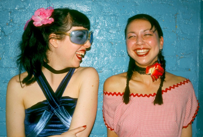 two young women in blue and red with flowers, one wearing Blue Sunglasses, © Margaret Schnipper, photographer