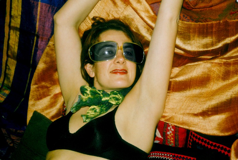 Laure lies on Moroccan silk, wearing Blue Sunglasses, © Margaret Schnipper, photographer