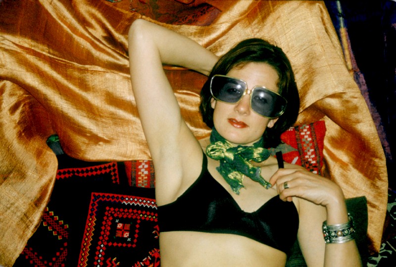 Laure lies on Moroccan silk, wearing Blue Sunglasses, © Margaret Schnipper, photographer